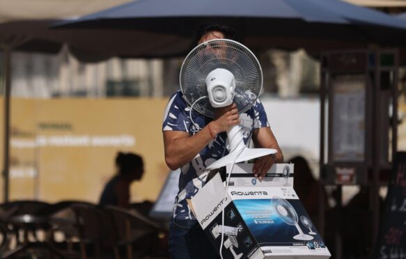 A man carries a fan as temperatures reach 38C in Montpellier, France.