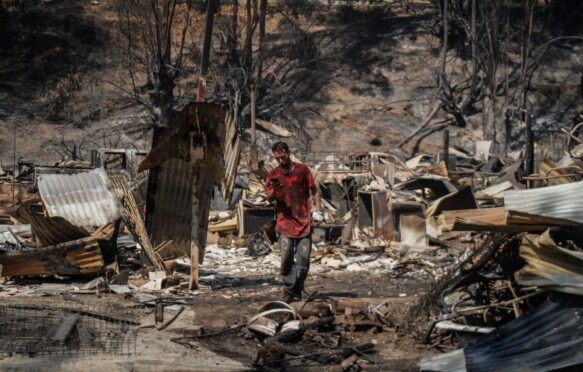 A person standing among the rubble from the Chilean “megafires”.