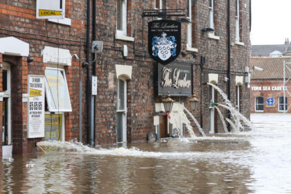 Water pours out of a flooded pub in North Yorkshire, UK.